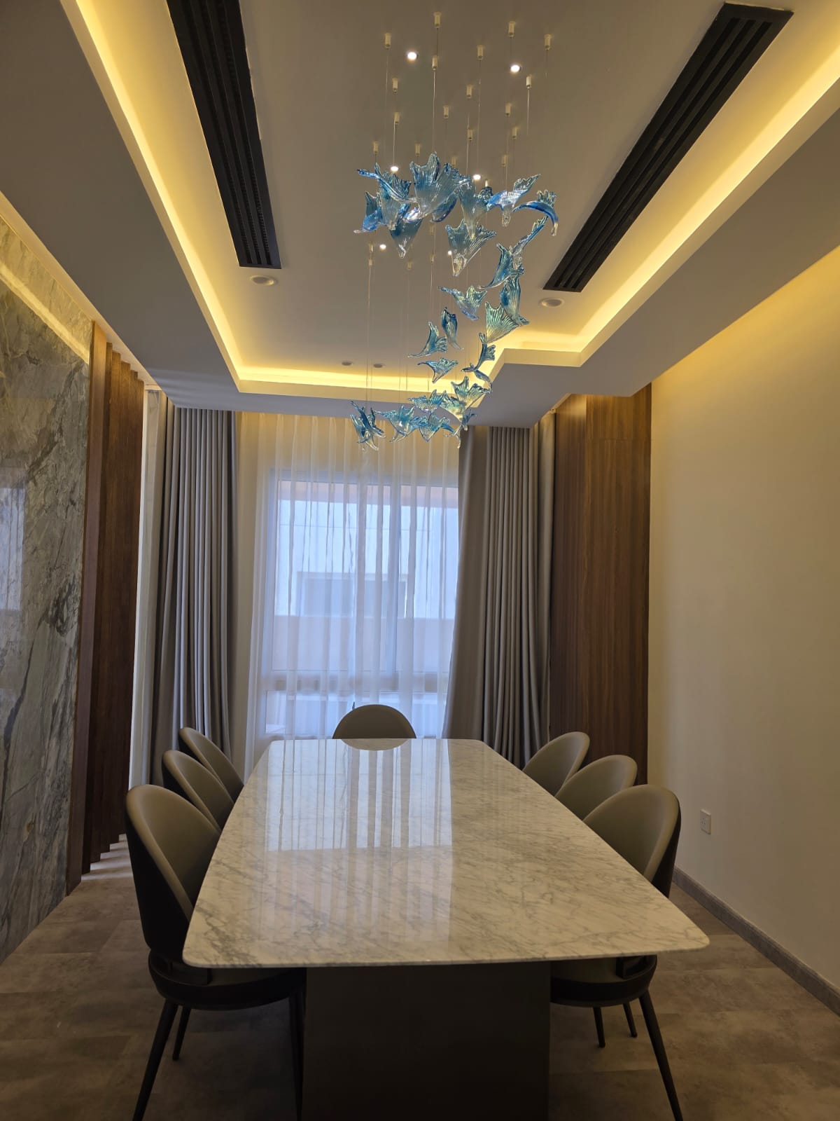 Pentazone-designed dining room with marble table and sculptural blue glass chandelier